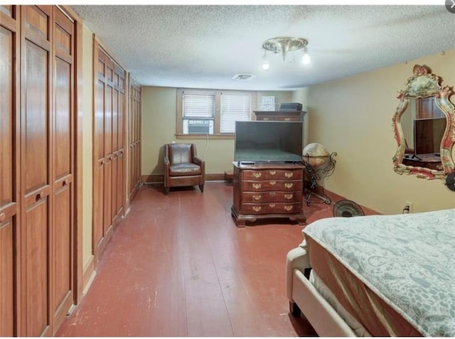 bedroom with a textured ceiling and dark hardwood / wood-style floors