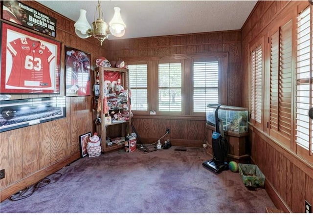 miscellaneous room with carpet, a chandelier, and wood walls