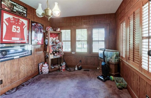 miscellaneous room with carpet flooring, an inviting chandelier, and wood walls