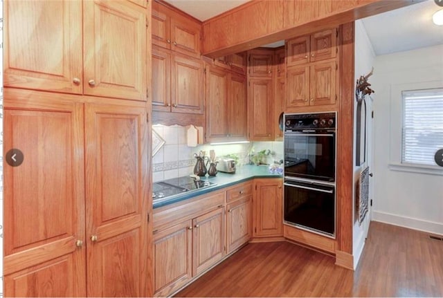 kitchen featuring light brown cabinets, light hardwood / wood-style flooring, tasteful backsplash, and black appliances