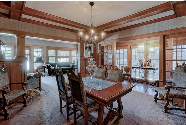 dining room featuring wood-type flooring, ornate columns, beamed ceiling, and an inviting chandelier