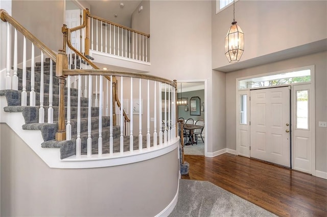 foyer entrance with a chandelier, dark hardwood / wood-style floors, and a towering ceiling