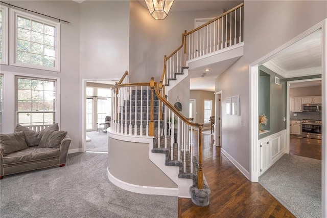 stairs with a towering ceiling, hardwood / wood-style floors, and a healthy amount of sunlight