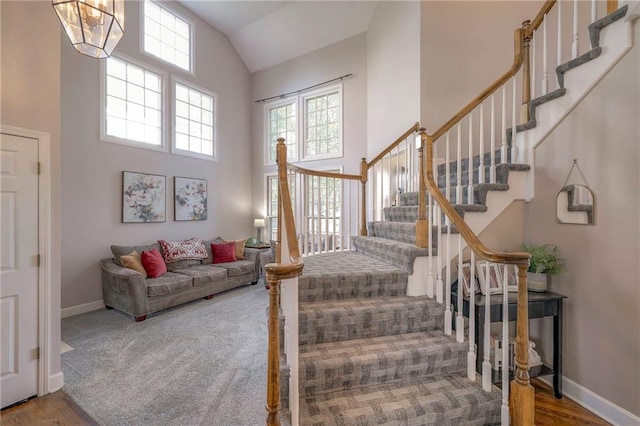 stairs featuring high vaulted ceiling, a wealth of natural light, and hardwood / wood-style floors