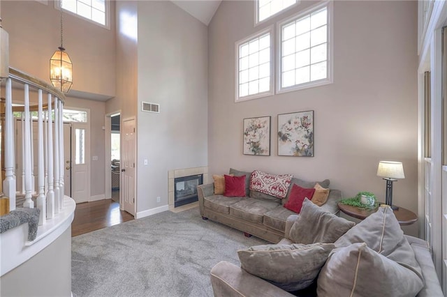 living room featuring high vaulted ceiling, a tile fireplace, and dark hardwood / wood-style floors