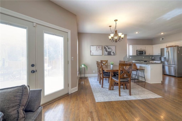 dining space with french doors, dark hardwood / wood-style floors, and an inviting chandelier