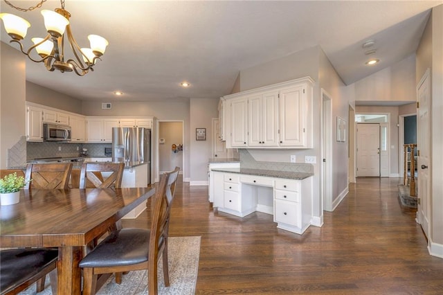 kitchen featuring white cabinets, an inviting chandelier, dark hardwood / wood-style floors, pendant lighting, and stainless steel appliances