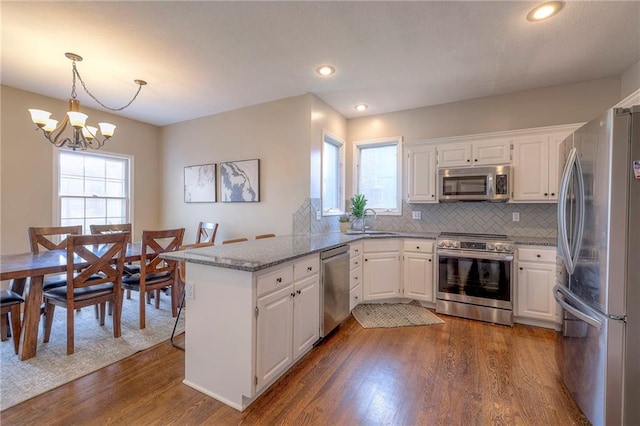 kitchen featuring appliances with stainless steel finishes, kitchen peninsula, white cabinets, and plenty of natural light