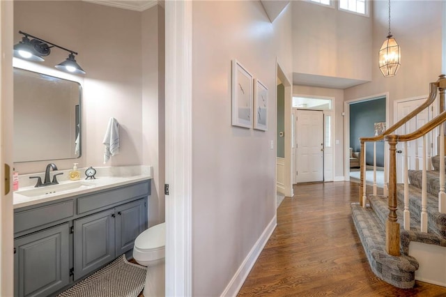 bathroom featuring a towering ceiling, toilet, vanity, crown molding, and hardwood / wood-style flooring