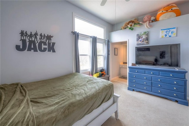 carpeted bedroom with ensuite bath and ceiling fan