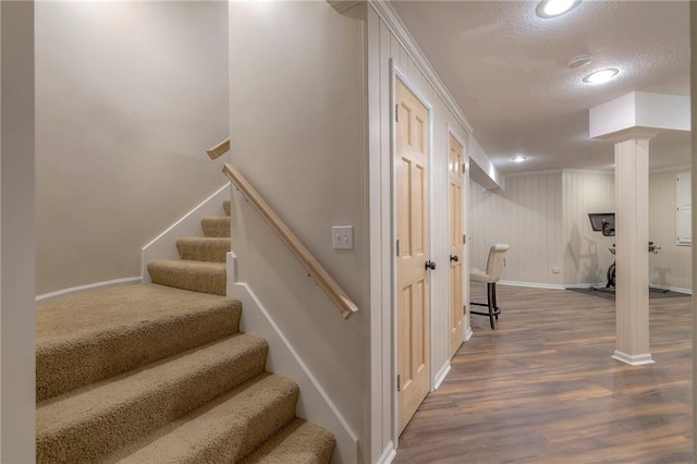 stairs with a textured ceiling, hardwood / wood-style flooring, and ornate columns