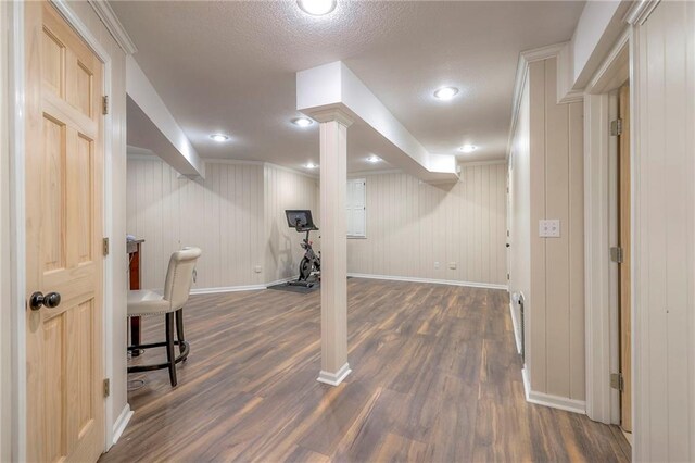 basement with dark wood-type flooring, a textured ceiling, and wooden walls