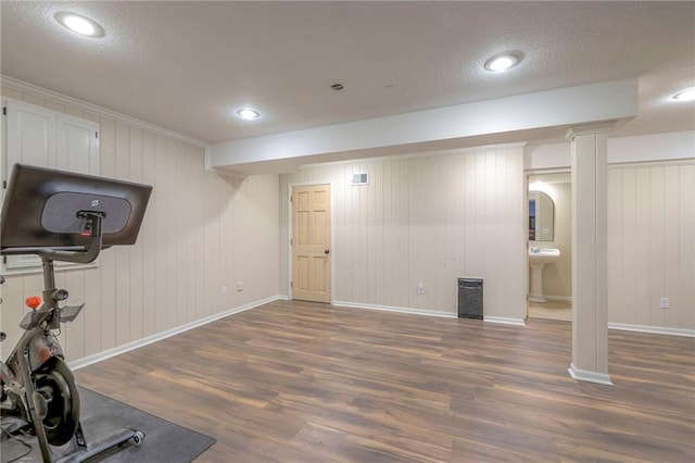 exercise room with wood walls, dark hardwood / wood-style floors, a textured ceiling, and sink