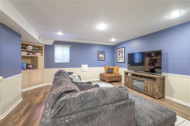 living room featuring a textured ceiling, built in shelves, and dark hardwood / wood-style flooring