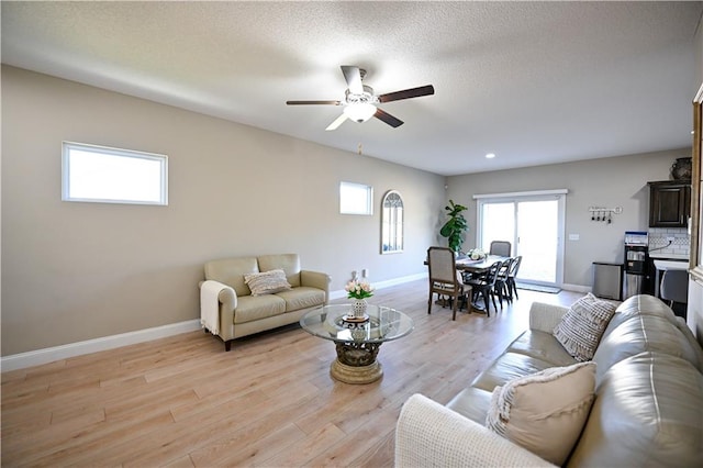 living room featuring light hardwood / wood-style flooring, a textured ceiling, and ceiling fan