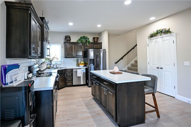 kitchen with decorative backsplash, a breakfast bar area, light hardwood / wood-style flooring, stainless steel appliances, and a center island