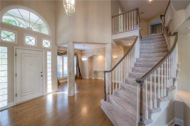 entryway with a towering ceiling, wood-type flooring, and plenty of natural light