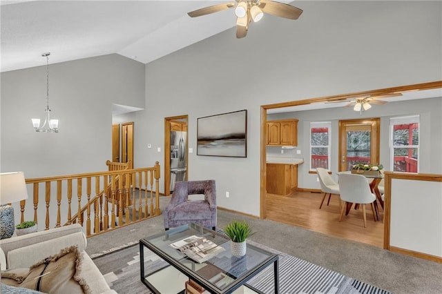 living room with ceiling fan with notable chandelier, light hardwood / wood-style floors, and high vaulted ceiling