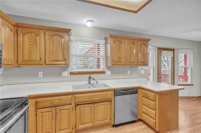 kitchen with kitchen peninsula, sink, stainless steel appliances, and light hardwood / wood-style floors