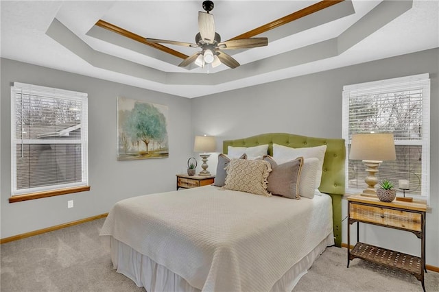 carpeted bedroom with ceiling fan, ornamental molding, and a tray ceiling