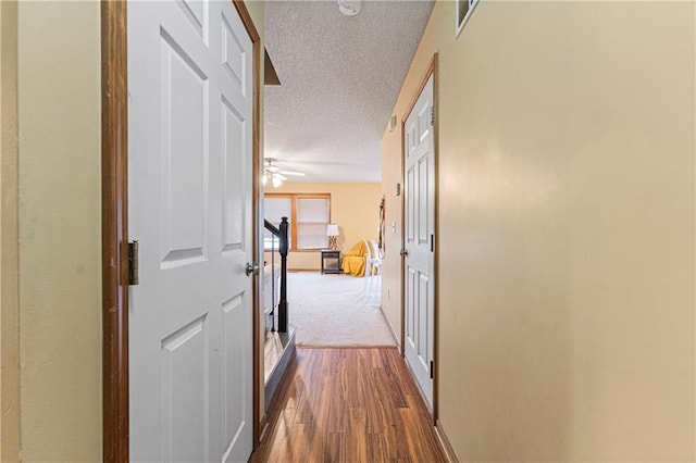 hallway with dark hardwood / wood-style floors and a textured ceiling