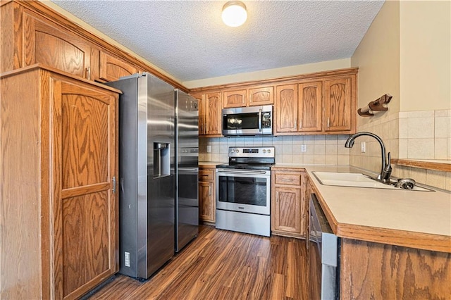 kitchen featuring appliances with stainless steel finishes, sink, decorative backsplash, dark wood-type flooring, and a textured ceiling