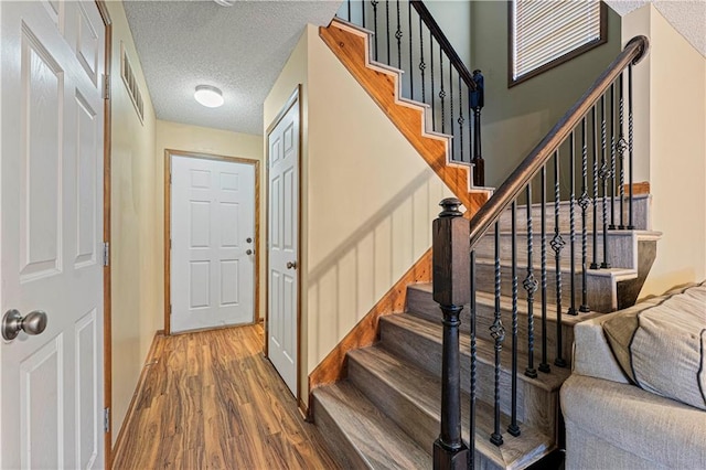 staircase with wood-type flooring and a textured ceiling