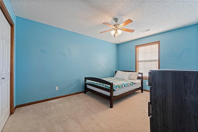 bedroom with light carpet, a textured ceiling, a closet, and ceiling fan