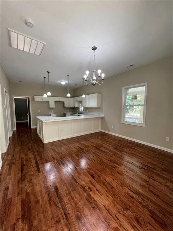 kitchen with kitchen peninsula, hanging light fixtures, white cabinetry, dark hardwood / wood-style floors, and a notable chandelier