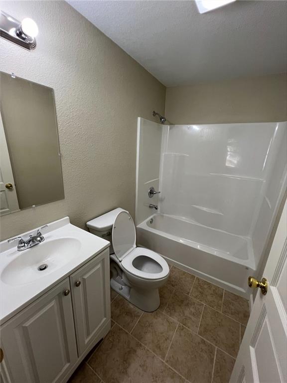601 W 5th St, Pittsburg, KS 66762 - bathroom with toilet, vanity, bathing tub / shower combination, a textured wall, and a textured ceiling