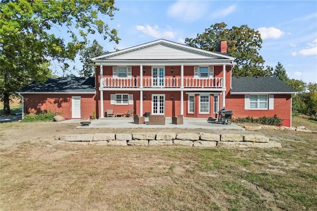 rear view of property featuring a balcony, a patio, and a lawn