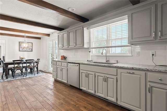 kitchen featuring sink, backsplash, dark hardwood / wood-style flooring, stainless steel dishwasher, and beam ceiling