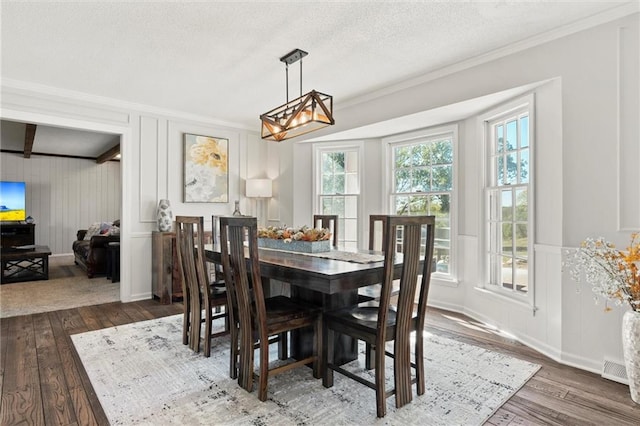 dining area featuring dark wood-type flooring, ornamental molding, and a textured ceiling