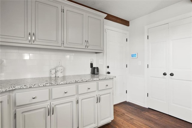 kitchen with light stone countertops, dark hardwood / wood-style floors, and white cabinets