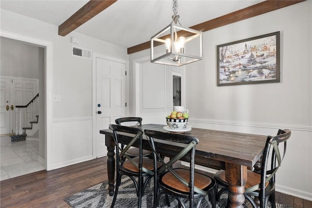 dining area featuring beam ceiling, dark wood-type flooring, and an inviting chandelier