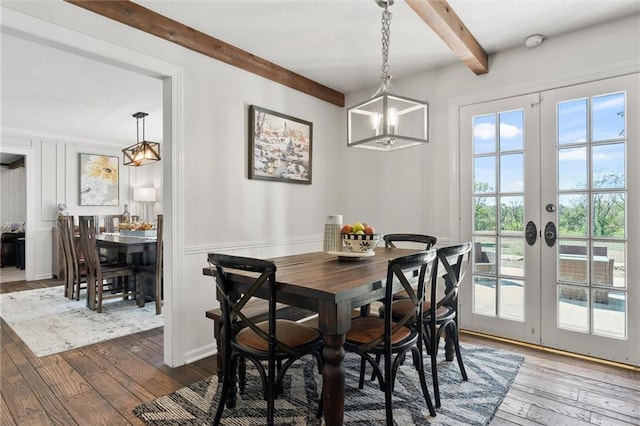 dining area featuring french doors, beam ceiling, a healthy amount of sunlight, and wood-type flooring