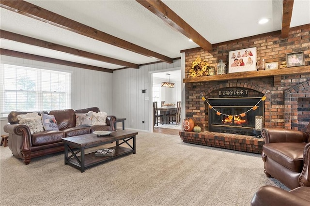 living room featuring beam ceiling, carpet flooring, and a brick fireplace