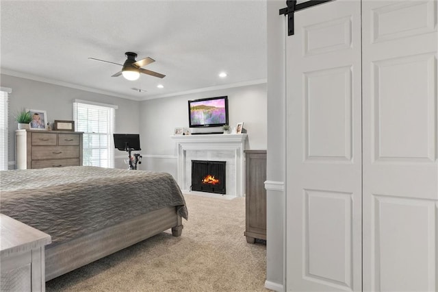 carpeted bedroom with a closet, ornamental molding, a barn door, and ceiling fan