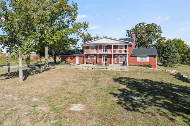 rear view of property featuring a balcony and a lawn