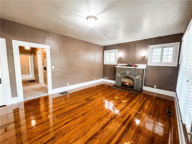 unfurnished living room featuring a brick fireplace and hardwood / wood-style floors