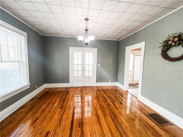 unfurnished dining area featuring a wealth of natural light, ornamental molding, hardwood / wood-style floors, and an inviting chandelier