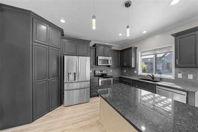 kitchen featuring light hardwood / wood-style flooring, sink, decorative light fixtures, appliances with stainless steel finishes, and tasteful backsplash