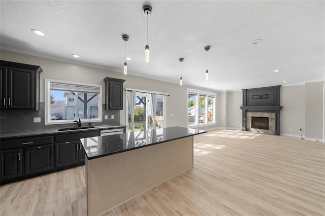 kitchen featuring decorative backsplash, a tiled fireplace, a center island, and hanging light fixtures