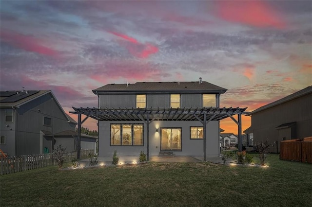 back house at dusk with a pergola, a patio area, and a lawn