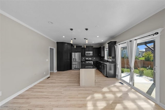 kitchen featuring appliances with stainless steel finishes, a center island, ornamental molding, light hardwood / wood-style floors, and decorative light fixtures