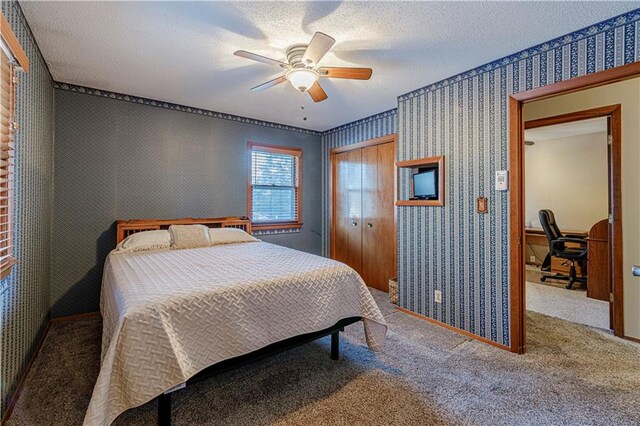 bedroom featuring a textured ceiling, carpet flooring, ceiling fan, and a closet