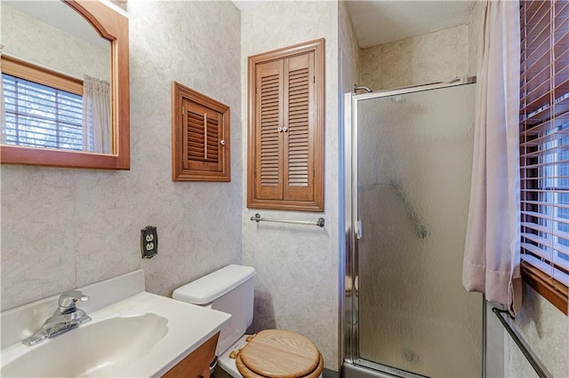 bathroom featuring vanity, toilet, and a shower with shower door