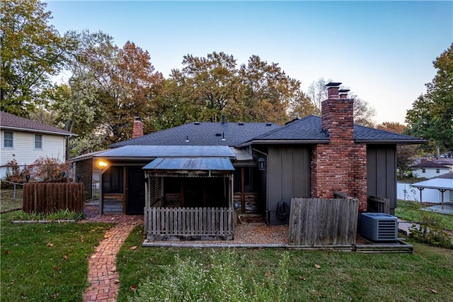 back of house featuring central AC unit and a yard