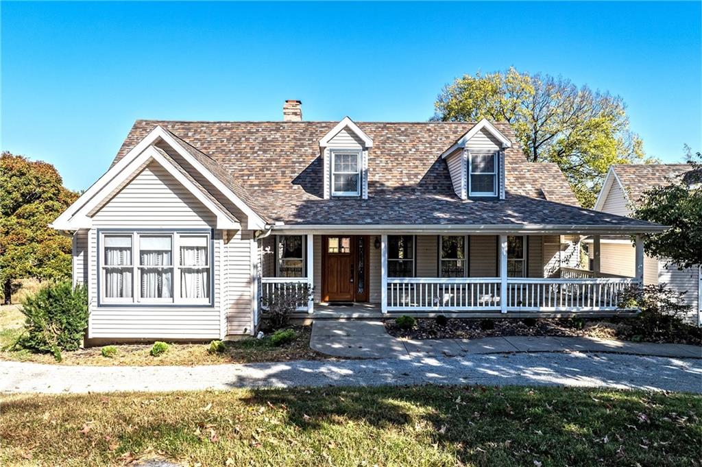 cape cod-style house featuring a front yard and a porch