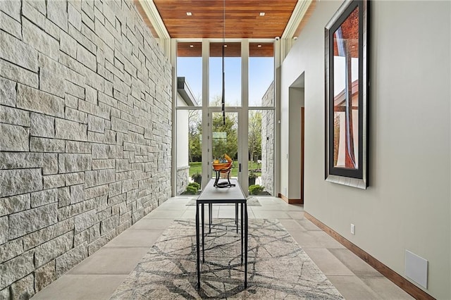 hall with wood ceiling, a high ceiling, and a wall of windows